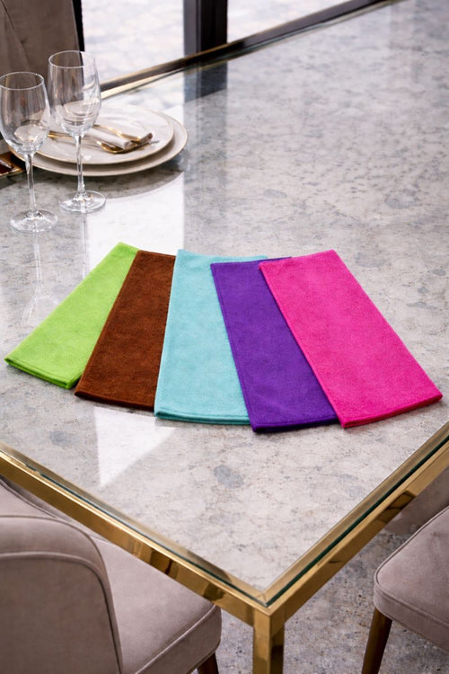 Vorre 320 GSM basic microfiber cleaning cloths in multiple colors fanned out on a marble dining table.