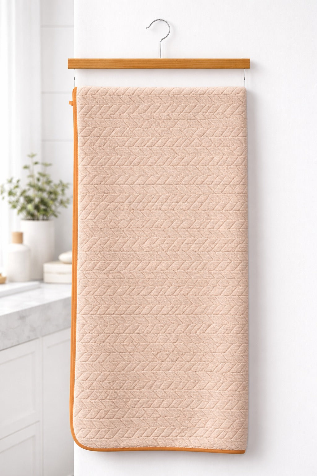 Warm peach cream neutral-toned Vorre Blush microfiber bath towel, soft everyday personal care towel on a wooden hanger.