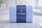 Packaged sky blue Vorre Blush textured microfiber bath towel featuring a premium branded navy blue belly band.