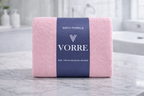Packaged soft baby pink Vorre Blush microfiber bath towel showing fine stitched edge details and a dark blue brand label.