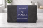 Packaged charcoal grey Vorre Classic microfiber bath towel wrapped with a premium navy blue product label band.