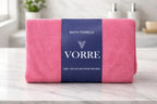 Packaged coral pink Vorre Classic microfiber bath towel wrapped with a signature dark blue belly band displaying the minimalist brand logo.