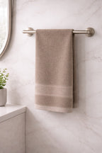 Beige tan Vorre Norvelle 400 GSM cotton hand towel hanging neatly on a modern bathroom rack.
