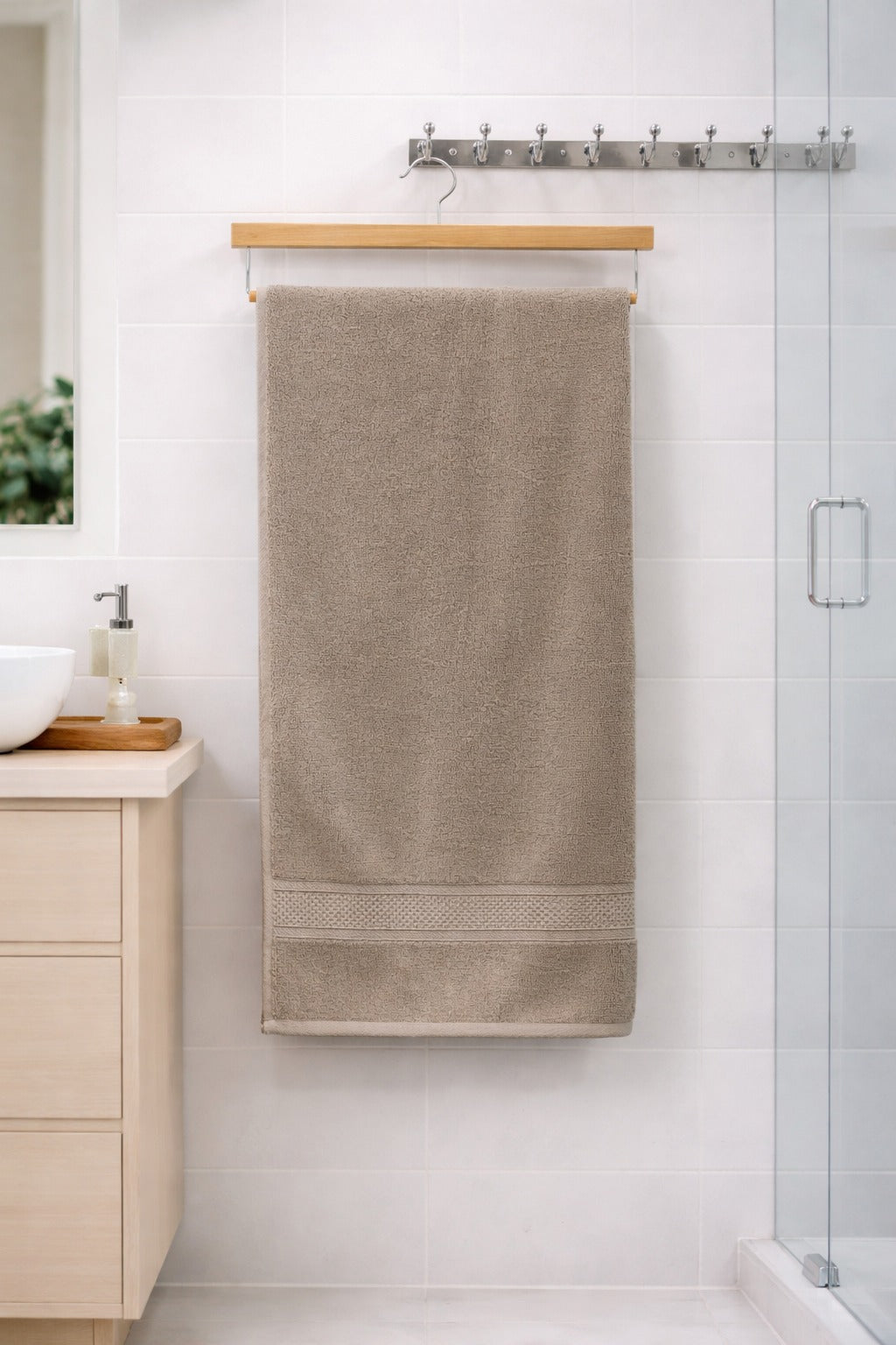 Beige taupe neutral-toned Vorre Norvelle recycled cotton bath towel, durable 400 GSM terry loop fabric body sheet displayed on a wooden hanger.