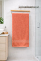 Coral pink Vorre Norvelle recycled cotton bath towel, quick-drying 400 GSM plush terry loop bath towel against a modern bathroom background.