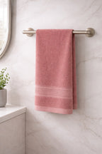 Coral peach Vorre Norvelle recycled cotton hand towel hanging on a metal rail in a bright bathroom.