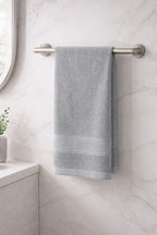 Soft grey Vorre Norvelle skin-friendly recycled cotton hand towel hanging in a tiled bathroom.