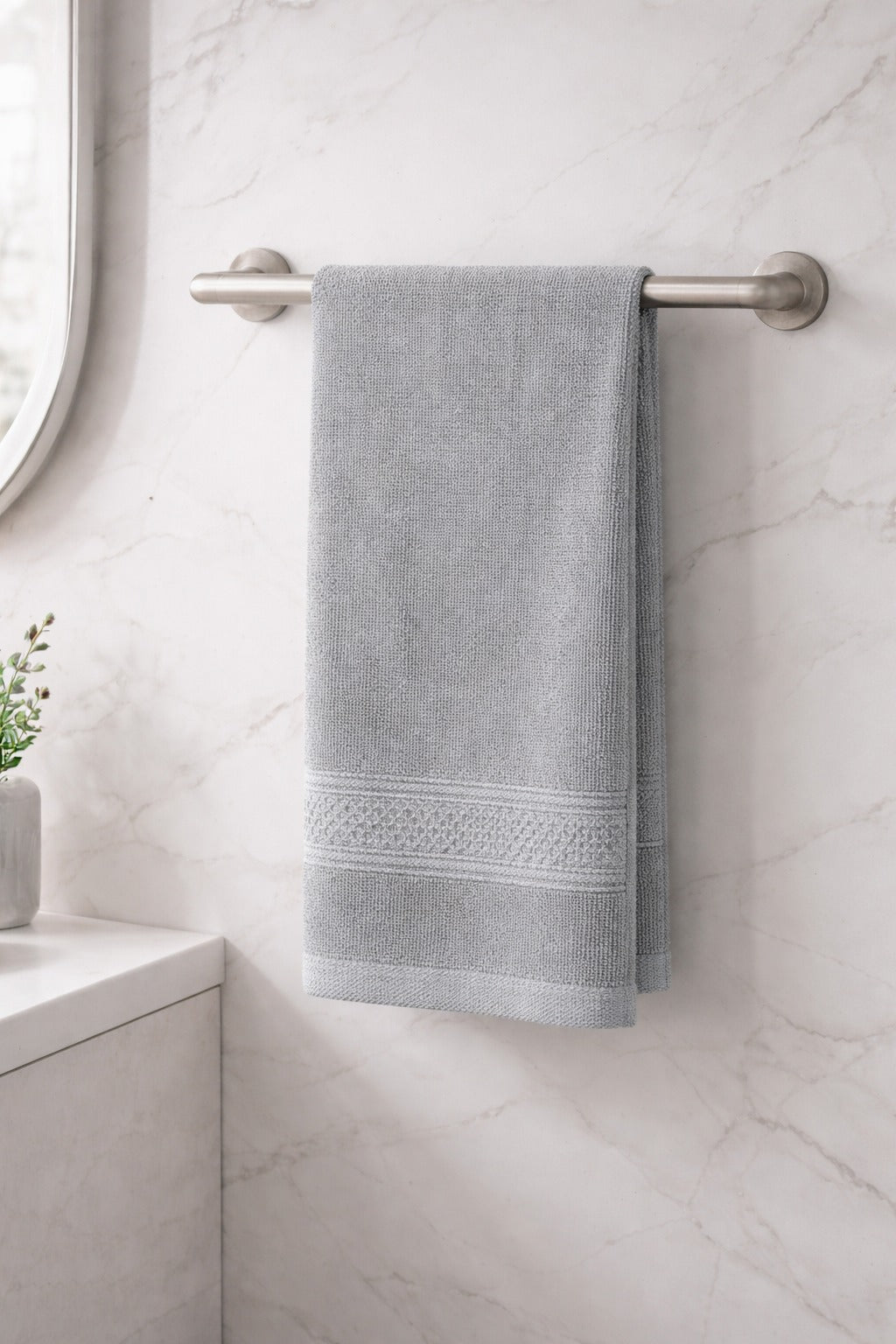 Soft grey Vorre Norvelle skin-friendly recycled cotton hand towel hanging in a tiled bathroom.