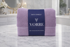 Packaged lavender purple Vorre Norvelle recycled cotton bath towel with a signature dark blue luxury paper wrapper sleeve.
