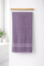 Lavender purple Vorre Norvelle recycled cotton bath towel, 400 GSM terry loop weave towel with elegant dobby border hanging on a bathroom rod.