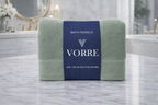 Packaged sage green Vorre Norvelle recycled cotton bath towel wrapped with a premium navy blue product label belly band.