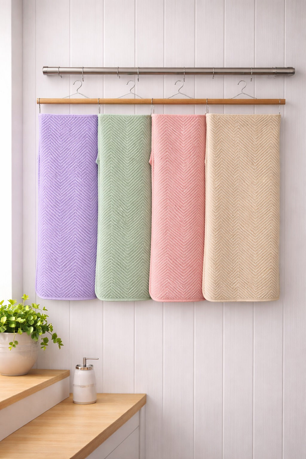 Four assorted colors of textured Vorre Pattern microfiber bath towels featuring fine geometric prints hanging on a wooden towel rack.