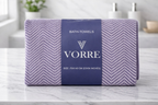 Packaged lavender purple textured Vorre microfiber bath towel neatly folded and wrapped with a signature dark blue brand band.