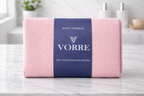 Packaged soft pink diamond patterned Vorre microfiber bath towel with a dark blue luxury paper wrapper sleeve.