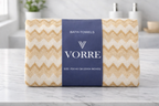Packaged cream gold zig-zag Vorre microfiber bath towel featuring a dark blue signature brand sleeve wrapper.