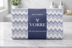 Packaged light grey chevron pattern Vorre microfiber bath towel neatly folded and wrapped with a navy blue luxury brand band.