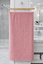 Coral pink vertical ribbed Vorre Ripped microfiber bath towel, highly absorbent everyday utility towel hanging neatly.