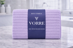 Packaged lavender purple ribbed texture Vorre microfiber bath towel showing a signature navy product wrapper band.
