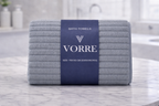 Packaged slate grey textured ribbed Vorre microfiber bath towel with a dark blue luxury paper wrapper sleeve.