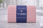 Packaged soft pink vertical ribbed Vorre microfiber bath towel featuring a premium branded packaging band.