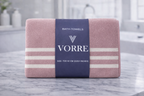 Packaged dusty rose pink striped Vorre microfiber bath towel with a signature dark blue luxury paper wrapper.