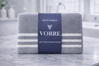 Packaged grey striped Vorre microfiber bath towel featuring a premium branded packaging sleeve on a marble counter.