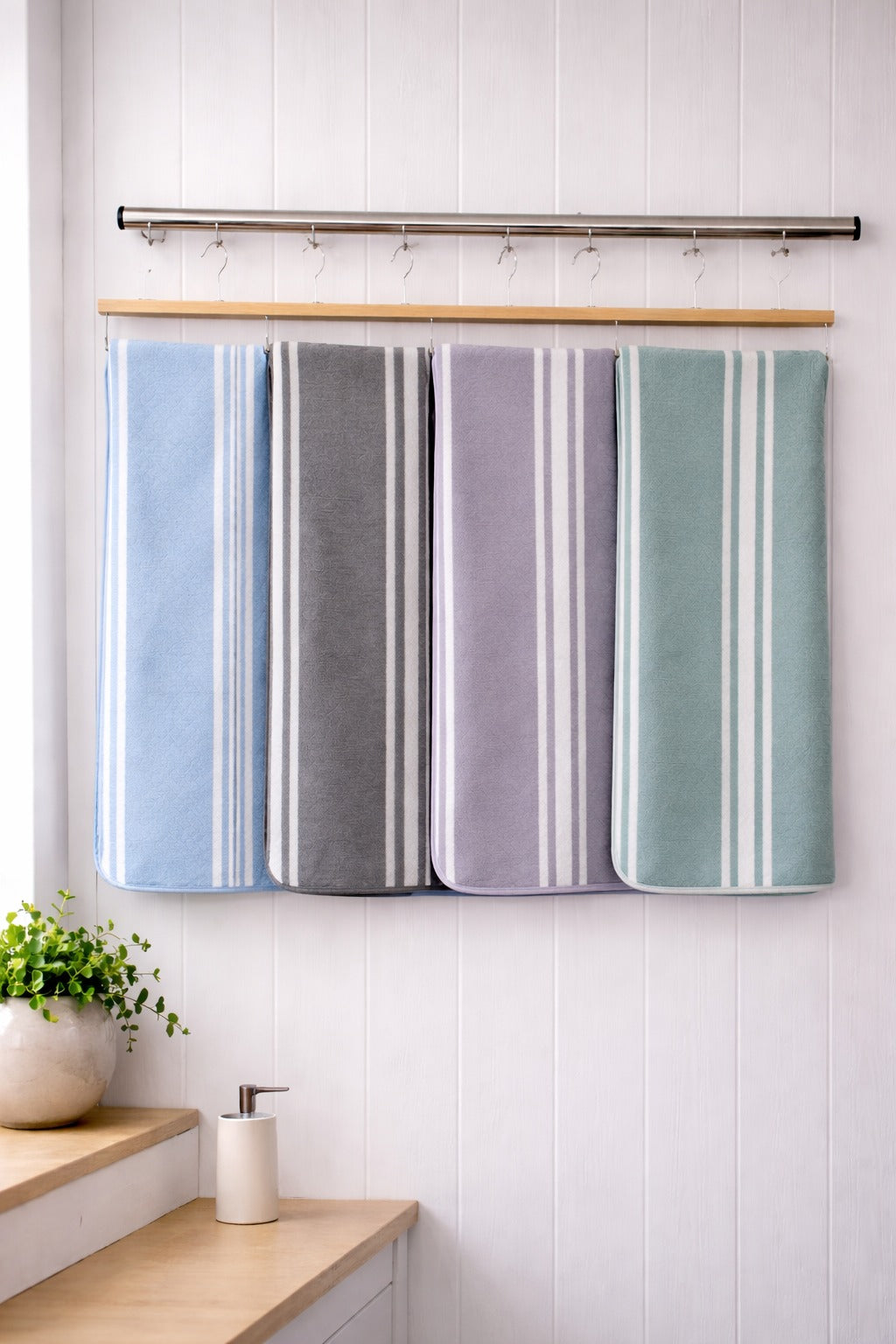 Six assorted colors of Vorre Stripe microfiber bath towels with white vertical stripe accents hanging on a modern bathroom towel bar.