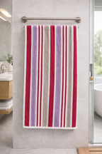 Pink, purple, and cream multi-toned striped Vorre cotton bath towel, plush 460 GSM luxury towel hanging on a rod.