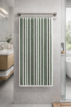 Muted sage green and white vertical striped Vorre cotton bath towel, natural luxury eco-friendly style towel hanging on a rack.